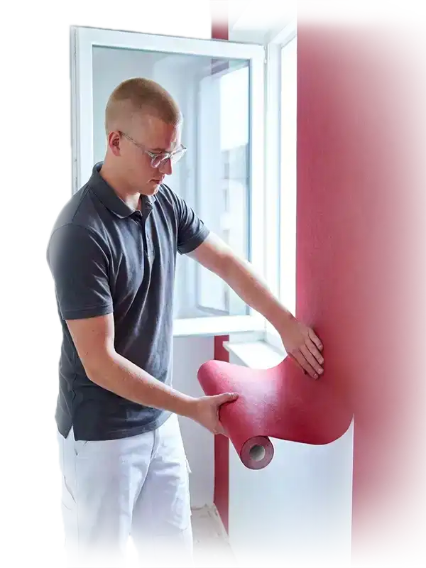 Maler tapeziert eine Wand mit roter Tapete in einer Wohnung in Fürth